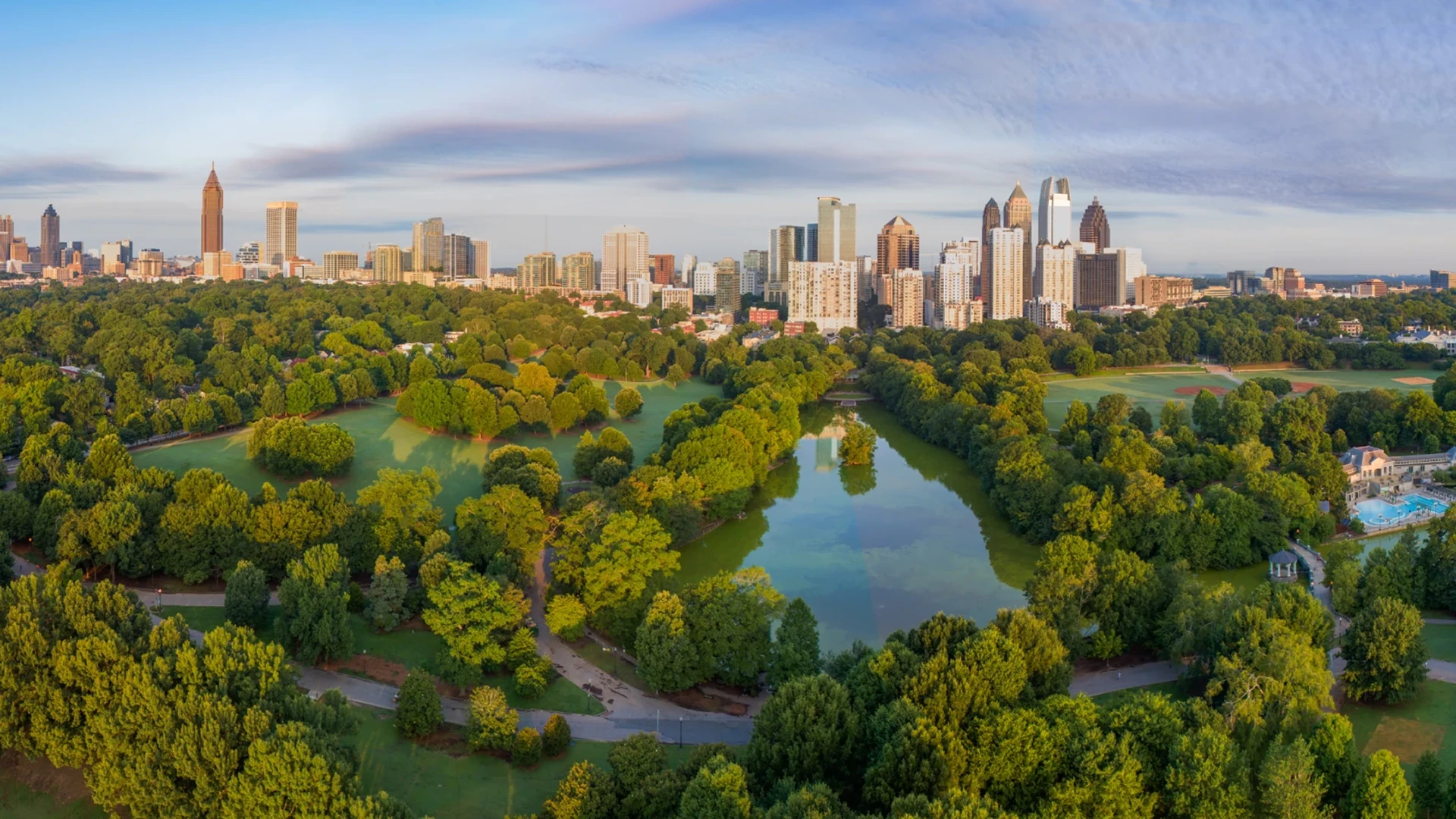 Atlanta skyline above green park with lake and trees at sunrise